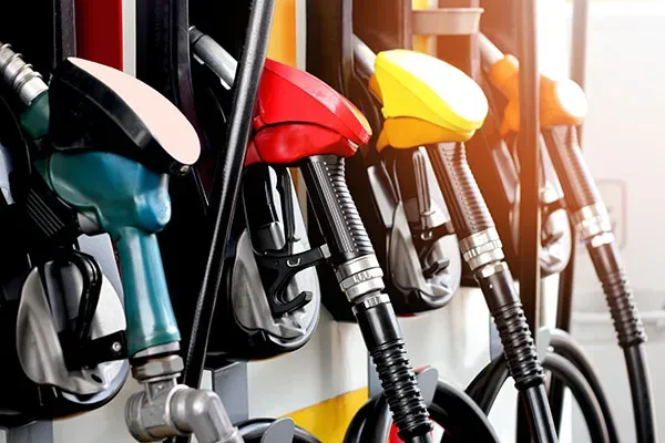 Row of colorful fuel nozzles at a gas pump (red, teal, yellow) in a station setup