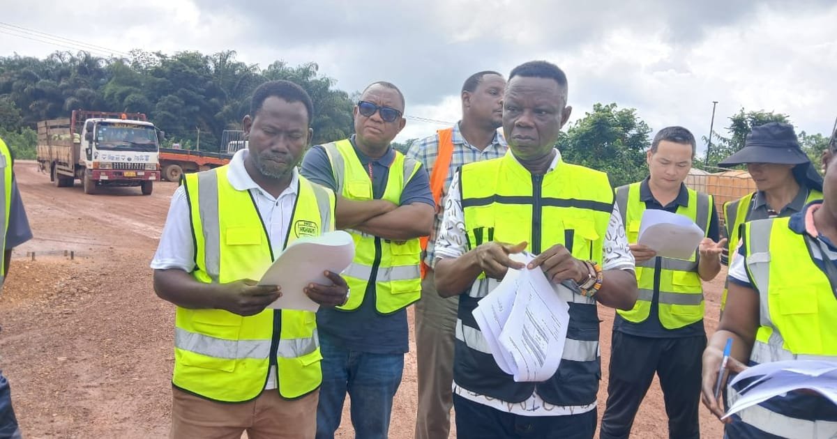 Group of construction workers in neon safety vests reviewing papers on a dirt road site.]','Group of surveyors at a construction site in reflective vests, examining documents.